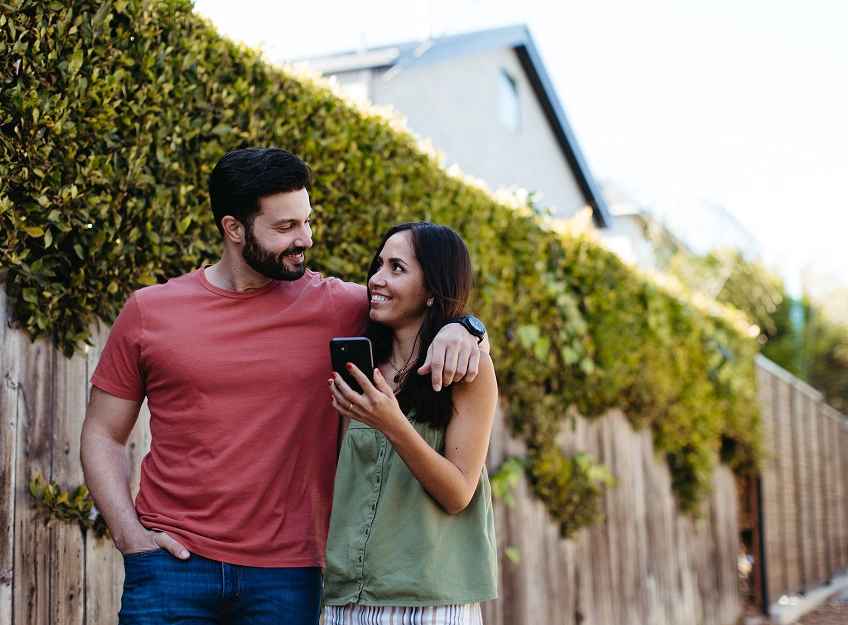 A couple looking at each and smiling as they walk together down the sidewalk