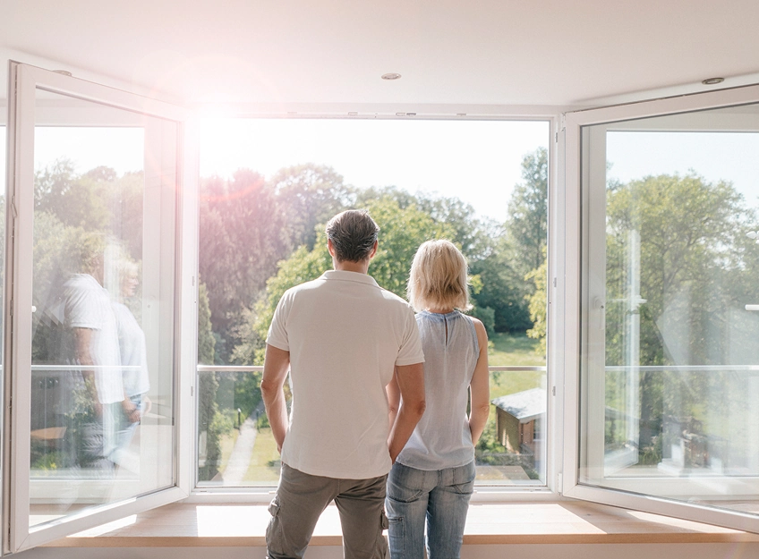 View of a couple looking out of a large open window from behind